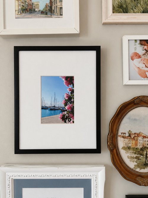 Wall with various framed pictures including a black-framed photo of the 5x7 print.
